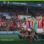 Torcida da Noruega com bandeiras nas arquibancadas durante partida da seleção norueguesa
